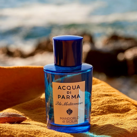 Blue Acqua di Parma bottle on a yellow towel with ocean background
