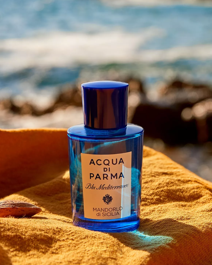 Blue Acqua di Parma bottle on a yellow towel with ocean background